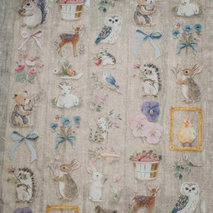 May include: A sheet of decorative stickers featuring woodland creatures and floral elements. The stickers include images of squirrels, deer, owls, rabbits, and bears, along with flowers and bows. The stickers are in soft pastel colors.