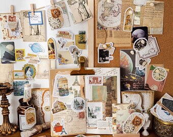 May include: A collection of vintage-style stickers, postcards, and ephemera, including images of planets, landscapes, and architectural landmarks. The items are arranged on a corkboard and wooden surface, with some clipped to a string with wooden clothespins.