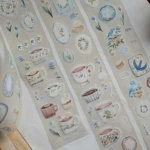 May include: Sticker strips with watercolour illustrations of teacups, plates, and floral elements in pastel shades. The stickers include images of birds, lemons, and small cakes, ideal for scrapbooking or craft projects.