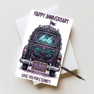 May include: A greeting card featuring a dark, gothic-style car illustration with purple and black accents, spiderwebs, and skulls. The text reads HAPPY ANNIVERSARY, TILL DEATH IS FOR QUITTERS, and LOVE YOU FOR ETERNITY. A black pen rests on the card.