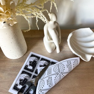 May include: A set of printable tarot cards featuring black and white illustrations of a woman with a crescent moon and stars. The cards are printed on white paper and are being cut with scissors. The text on the cards reads "SOMETIMES TWO SOULS ARE PHYSICALLY TALL APART, MOON THEY NEED TO FALL BACK" and "WHEN SOULS ELECTRICALLY CONNECT VIA THE HEART, TIME AND SPACE DOES NOT HINDER COMMUNICATION."