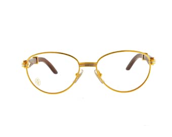 May include: Gold-tone oval-shaped eyeglasses with brown wood accents on the arms. The glasses have clear lenses.