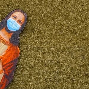 Puede incluir: Un retrato de Jesús con una mascarilla facial azul. La imagen está sobre un fondo marrón.