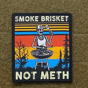 Może przedstawiać: Czarno-biała łatka z retro wzorem. Szkielet w czapce kucharza i fartuchu griluje mięso na grillu. Na łatce nadrukowany jest tekst "SMOKE BRISKET NOT METH".