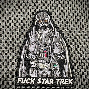 以下が含まれることがあります： ダース・ベイダーが中指を立てている黒と白の刺繍パッチ。下に「FUCK STAR TREK」の文字が書かれている。