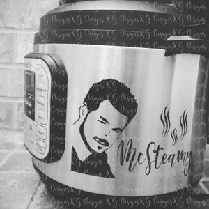 May include: A stainless steel Instant Pot, decorated with a black and white decal. The decal features a man's portrait and the cursive text "McSteamy". The appliance has several function buttons.