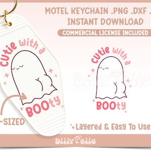 以下が含まれることがあります： ピンクの輪郭とピンクの文字「Cutie with a Booty」が書かれた白いモテルのキーホルダー。キーホルダーには、ピンクの輪郭とピンクの文字「Cutie with a Booty」が書かれた漫画の幽霊が描かれています。キーホルダーは事前にサイズが決められており、簡単に使用できるように重ねられています。