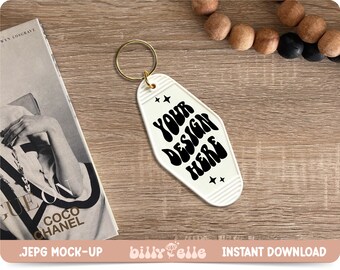 May include: White motel key tag with a gold key ring. The tag has a black retro font that says "YOUR DESIGN HERE" with two small stars on either side of the text.