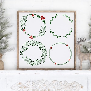 May include: Four different Christmas wreath designs with green leaves and red berries. The wreaths are displayed on a white sign with a wood frame.