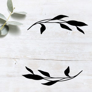May include: Two black silhouette images of leafy branches on a white wood background. The branches are arranged in a symmetrical design, with one branch at the top and one at the bottom.