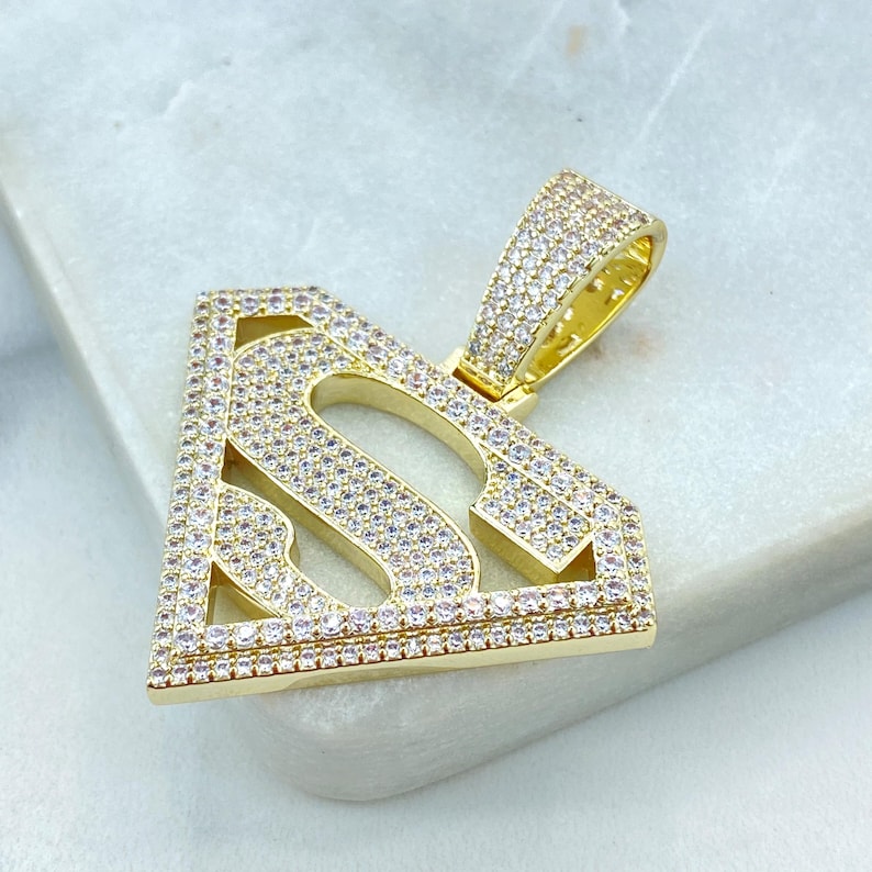 Puede incluir: Colgante de oro con un dise&ntilde;o de logotipo de Superman con piedras de circonita c&uacute;bica transparentes.
