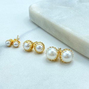 May include: Four pairs of gold stud earrings with white pearl accents. The earrings vary in size, with the largest pair featuring a scalloped gold setting. The pearls have a lustrous sheen.