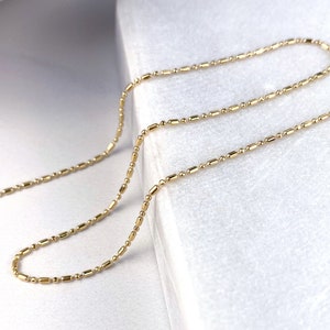 May include: A gold chain necklace with a delicate, round-shaped link design. The chain is laid out on a white surface.