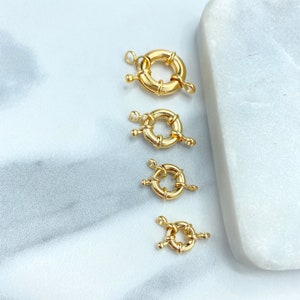 May include: Four gold-toned metal ring clasps of varying sizes. The clasps are designed with a circular shape and a decorative twist detail.