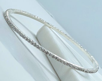May include: A silver bangle bracelet with a row of clear rhinestones around the edge.