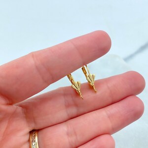 May include: A pair of gold-toned earring hooks with a small, flat, heart-shaped design at the top.