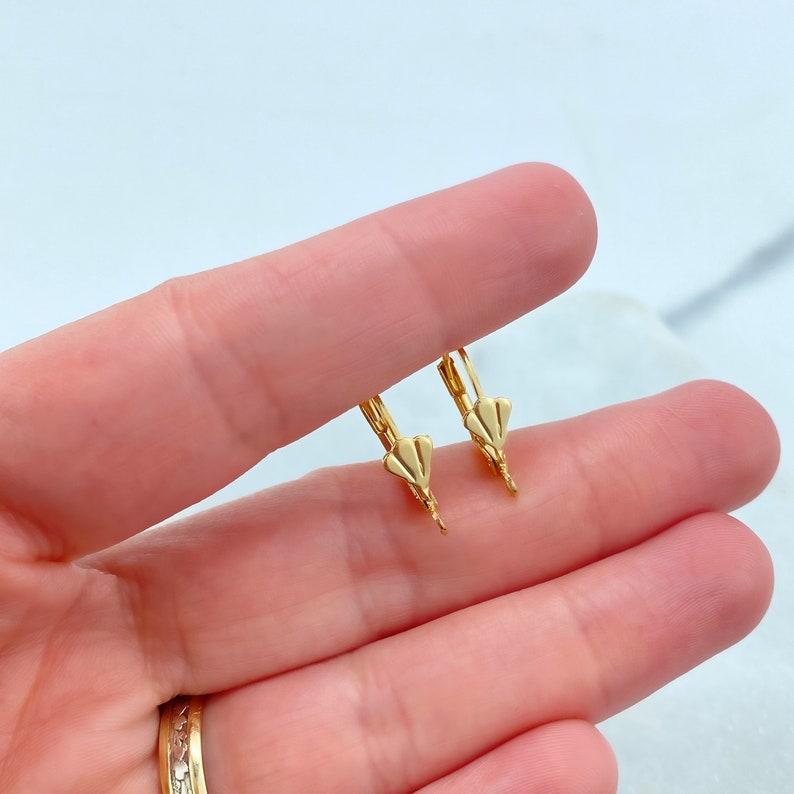 May include: A pair of gold-toned earring hooks with a small, flat, heart-shaped design at the top.