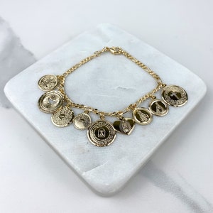 Pulsera con dijes de monedas religiosas bañadas en oro de 18 quilates: San Agustín, Paloma, Virgen de Guadalupe, Virgen de los Milagros, Padre Nuestro. Venta al por mayor.