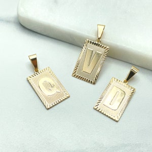 May include: Gold-colored rectangular pendants with the letters Q, V, and D. Each pendant has a textured border and a loop for a chain. The letters are in a bold, sans-serif font.