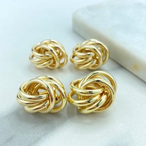May include: Four gold-toned knot-shaped earrings. The earrings are made of a thick, twisted metal.