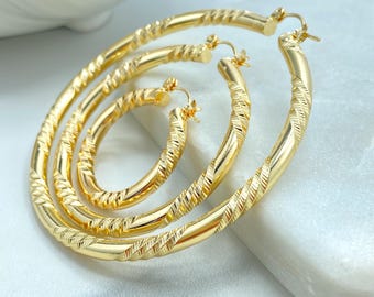 May include: Three pairs of gold-colored hoop earrings in varying sizes. Each hoop has a textured, ridged design. The earrings are displayed on a white surface, showcasing their shiny, metallic appearance. The earrings are a jewelry item.