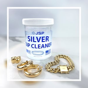 May include: A clear plastic bottle of silver dip cleaner with a blue label that reads "JSP SILVER DIP CLEANER".  The bottle is next to a gold chain bracelet with a 14K clasp and two gold hoop earrings.