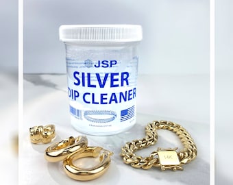 May include: A clear plastic bottle of silver dip cleaner with a blue label that reads "JSP SILVER DIP CLEANER".  The bottle is next to a gold chain bracelet with a 14K clasp and two gold hoop earrings.