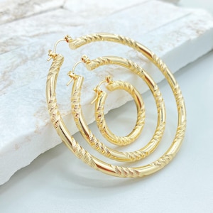 May include: Three gold-toned hoop earrings of varying sizes nested within each other. Each hoop features a continuous twisted, textured pattern along the entire circular band, with a simple hinged wire closure mechanism at the top of each earring.