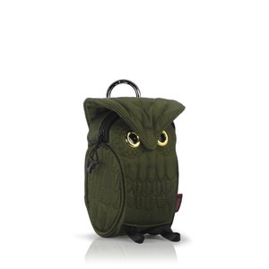 Peut inclure: Un petit sac vert matelassé en forme de hibou avec des yeux dorés et des accents noirs.