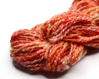 May include: A skein of yarn in shades of orange, pink, and white. The yarn is soft and fluffy, and it is perfect for knitting or crocheting.