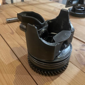 May include: A metal piston with a gear on the bottom, a lever on the side, and the text "1400000" on the side.