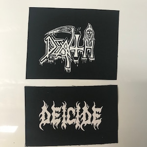 May include: Two black fabric patches with white lettering. The top patch features the word "DEATH" in a stylized font with a skull and scythe design. The bottom patch features the word "DECIDE" in a stylized font.