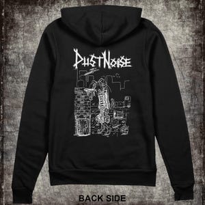 May include: Black hooded sweatshirt with a white graphic on the back. The graphic features the text "Dust Noise" above a detailed illustration of a figure in a city setting. The words "BACK SIDE" are printed at the bottom of the sweatshirt.