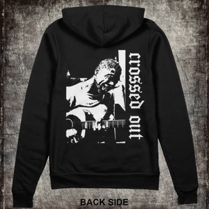 May include: Black hooded sweatshirt with a white graphic print of a person playing a guitar and the text "crossed out" on the back.