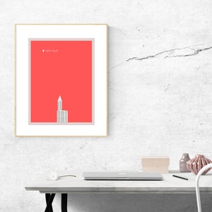 Könnte beinhalten: Ein gerahmter Druck einer minimalistischen Illustration eines Gebäudes mit dem Text "Smith Tower" in der oberen linken Ecke. Der Hintergrund ist einfarbig rot.