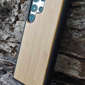 a smartphone case made of wood and black material, placed on a wooden surface.