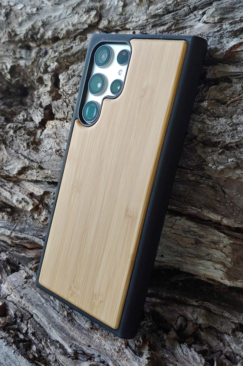 a smartphone case made of wood and black material, placed on a wooden surface.