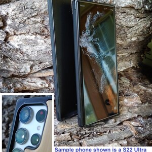 a sample phone with a black case, placed on a rock surface. The phone's screen displays the time and date, and the camera shape may vary across other models.