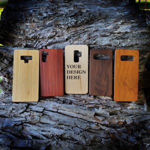 May include: Five rectangular phone cases made of different wood grains and colors, including light bamboo, reddish-brown, light maple with the text YOUR DESIGN HERE, dark walnut, and medium-toned cherry, each featuring a camera cutout at the top.