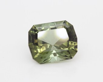 May include: A green gemstone with a rectangular cut and a faceted design.