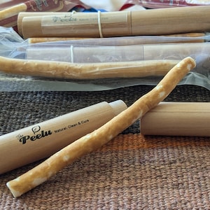 Könnte beinhalten: Nahaufnahme einer natürlichen, biologisch abbaubaren Zahnbürste aus Holz und Naturfaser. Die Zahnbürste befindet sich in einem Holzetui mit dem aufgedruckten Text "The Peeluu Natural, Clean & Cure". Die Zahnbürste ist eine nachhaltige Alternative zu Plastikzahnbürsten.