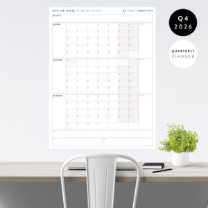 May include: A white quarterly planner for Q4 2026, with calendar grids for October, November, and December. The planner includes the text "PLAN THE THINGS // DO THE THINGS" and "QUARTERLY PLANNER". A small plant in a white pot sits on a desk.