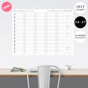 May include: A white wall calendar featuring a July start for the years 2026 and 2027. The grid displays months from July to June with aligned weekends. Text at the top reads PLAN THE THINGS // DO THE THINGS TWENTY TWENTY SIX / TWENTY TWENTY SEVEN.