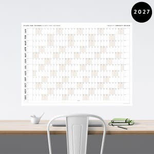 May include: A large, white 2027 wall calendar with a grid layout for monthly planning. The calendar has the text "PLAN THE THINGS // DO THE THINGS" at the top. A black circle with the year 2027 is in the upper right corner.