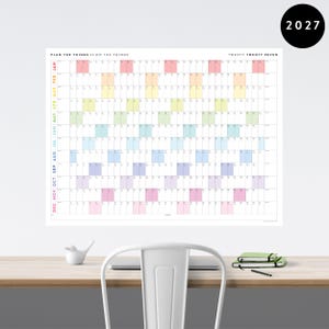 May include: A large wall calendar for the year 2027, featuring a grid layout with color-coded months. The calendar has the text "PLAN THE THINGS // DO THE THINGS" and "TWENTY TWENTY SEVEN". The months are labeled vertically on the left side.