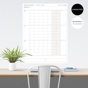 May include: A white undated quarterly planner with three sections for quarterly goals. The planner has a black header that says "Plan the things // Do the things" and a black footer that says "This is my time".