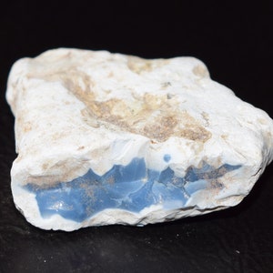 Könnte beinhalten: Ein rauer, weißer Stein mit einer blauen Opalader, die durch ihn verläuft. Der Opal ist hellblau und hat eine glatte, polierte Oberfläche.