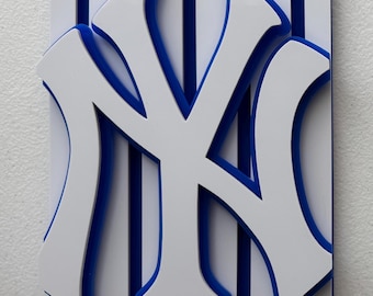 May include: White and blue 3D wall art featuring the New York Yankees logo. The logo is made of white plastic with blue outlines and is set against a background of blue and white stripes.