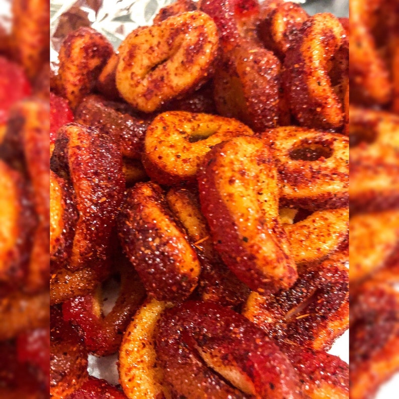 Puede incluir: Primer plano de un mont&oacute;n de caramelos picantes de color marr&oacute;n rojizo. Los caramelos tienen forma de anillo y est&aacute;n cubiertos con una generosa capa de chile en polvo y especias. La imagen est&aacute; bien iluminada, resaltando la textura y el color de los dulces.