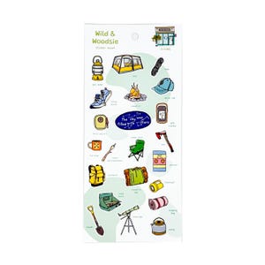 May include: A sticker sheet titled "Wild & Woodsie" featuring camping-themed illustrations. Includes a tent, campfire, hiking boots, backpack, and other outdoor adventure elements. The text "The sky was filled with stars" is also included.